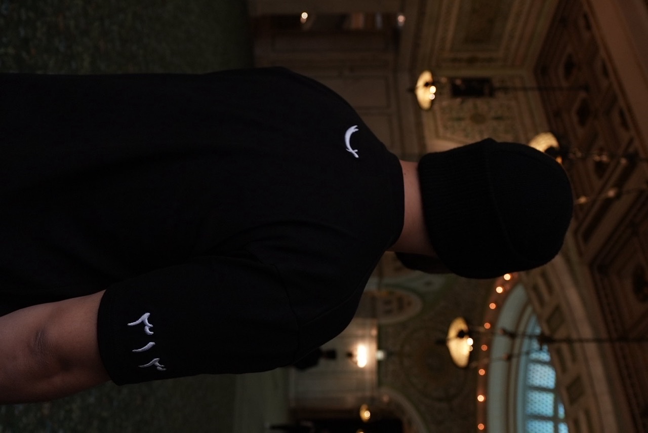 40 Nights tee seen from behind in an ornate hall, with the sword mark at the collar and 313 embroidered on the sleeve